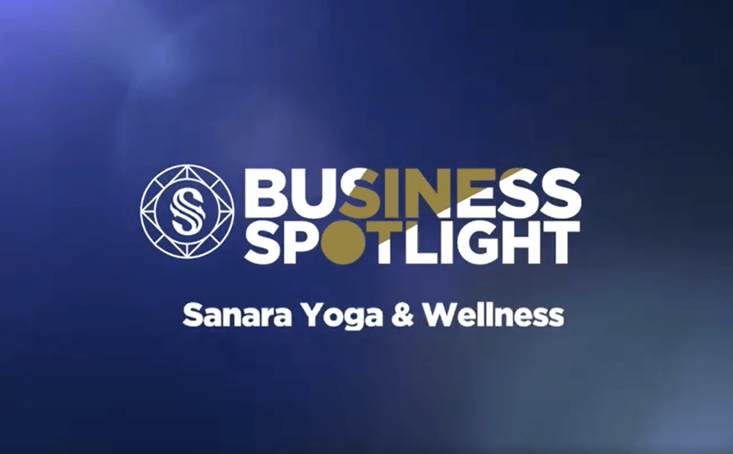 A blue background with white text that reads "Business Spotlight" accompanied by a geometric logo with an "S" inside. Below, the text "Sanara Yoga & Wellness" is written in white.