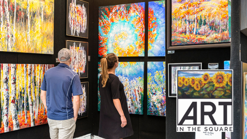 People looking at artwork hanging on the wall.