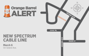 Map showing road work alert for a new Spectrum cable line on Grand Ave. The affected area is marked in orange dashes between Grand Ave and Civic Pl. Includes a compass rose indicating north. Title reads "Orange Barrel Alert" with an orange barrel icon. March 6.