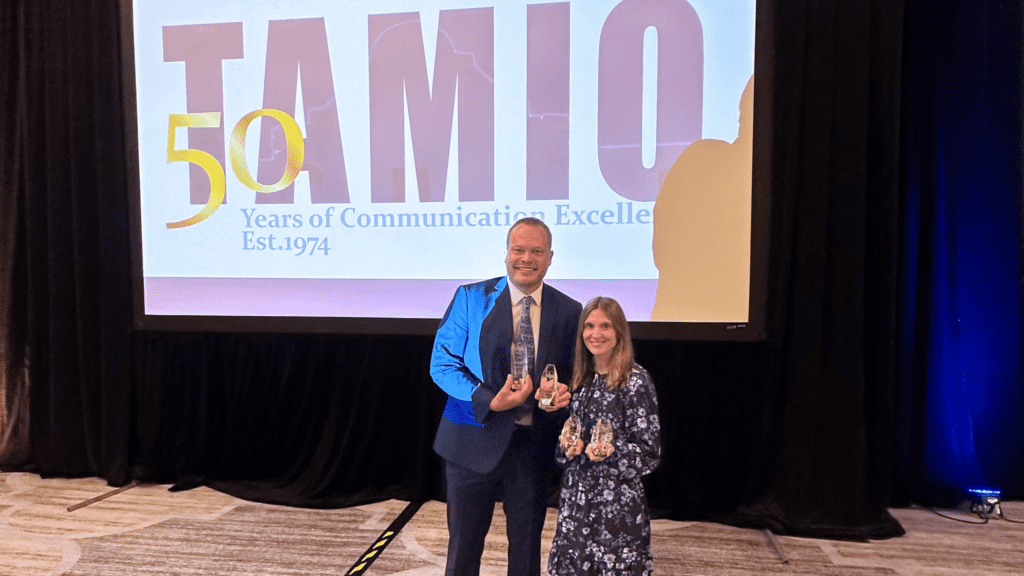 Photo of a man and a woman holding awards