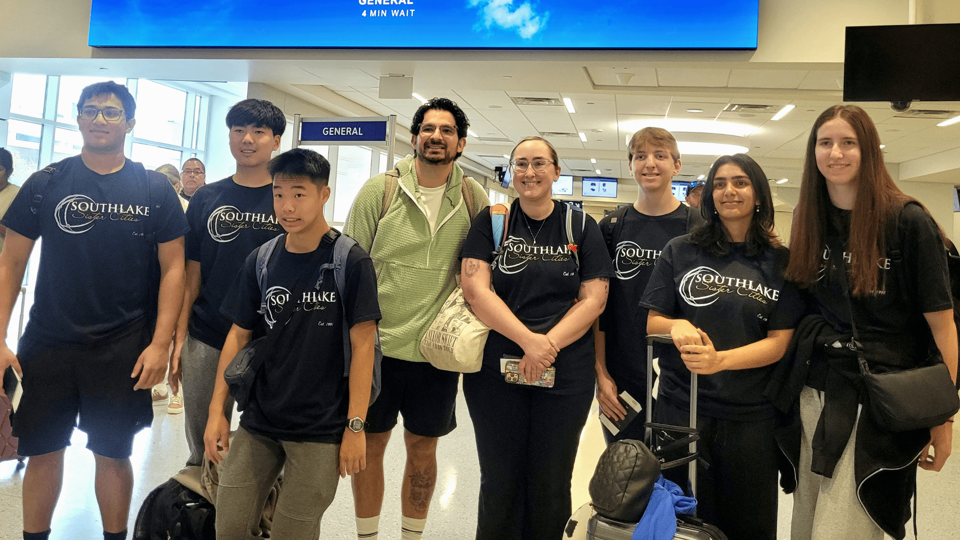A group of 8 high school students and 2 adult chaperones at the airport preparing to travel to japan