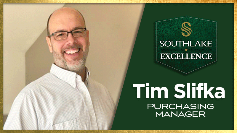 Man smiling, wearing glasses and a white shirt, next to a green plaque with "Southlake Excellence" and "Tim Slifka, Purchasing Manager" written on it. Background features a light, neutral wall.