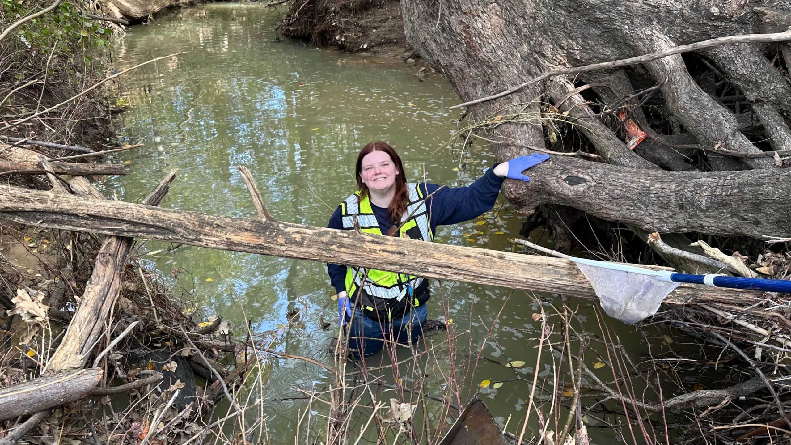 Photo of a woman in the water cleaning debris