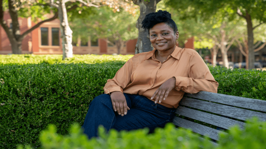 Library staff member Marva sitting on a park bench smiling.