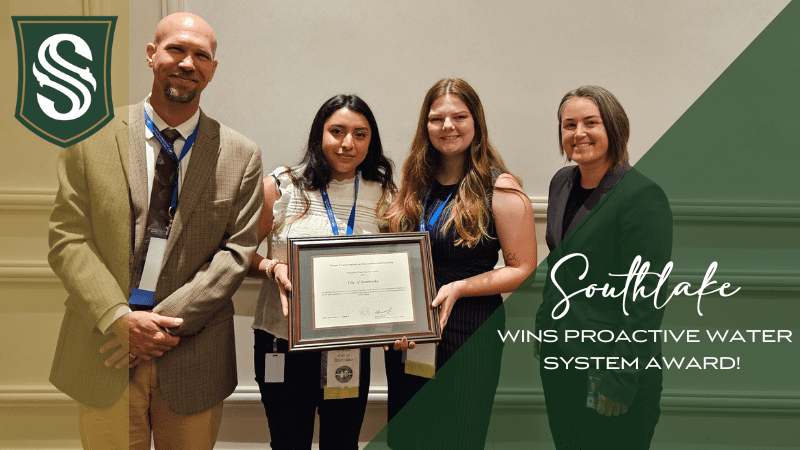 Four people stand together, smiling, holding a framed certificate. The background features a Southlake logo and text stating "Southlake Wins Proactive Water System Award!.