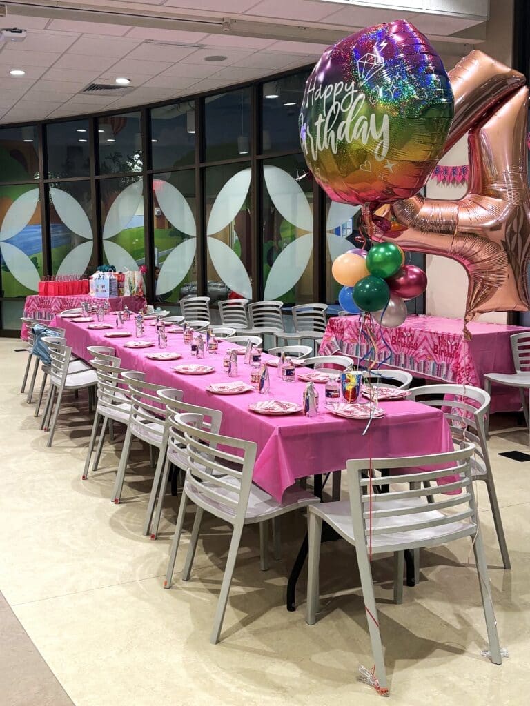 table and chairs set with party decorations and balloons